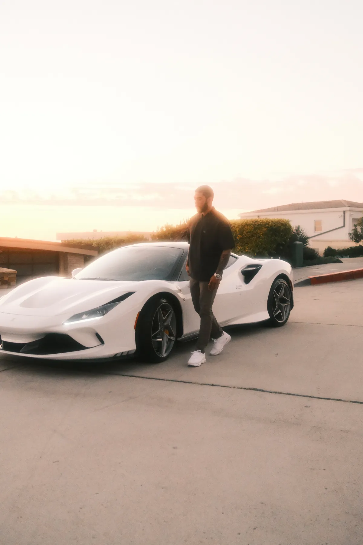 Nate Rodgers beside a white sports car at sunset